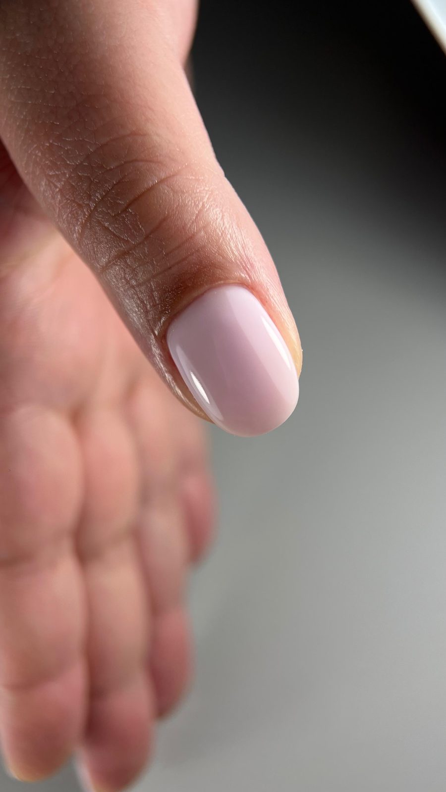 Close-up van een duim met melkwit roze BIAB