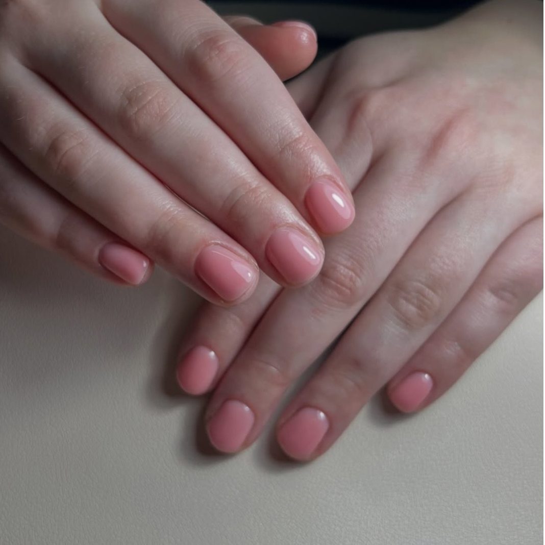 Roze nagels op twee handen aan tafel, van Ilse